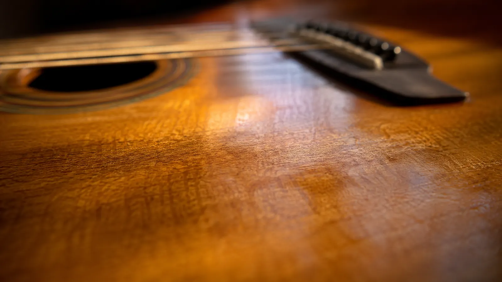 Close-up of an acoustic guitar soundboard showing natural wood grain in warm light