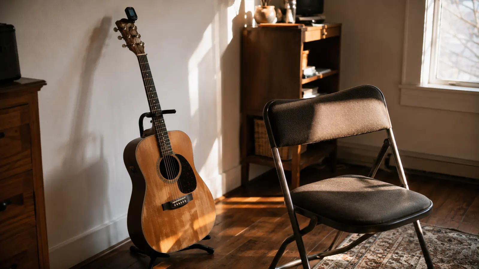 A home practice corner with an acoustic guitar on a stand in afternoon light.